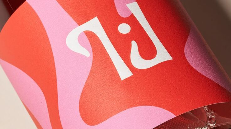 Modernes Etikett für eine Weinflasche in roter und rosaner Grafik mit einem weißen Logo.