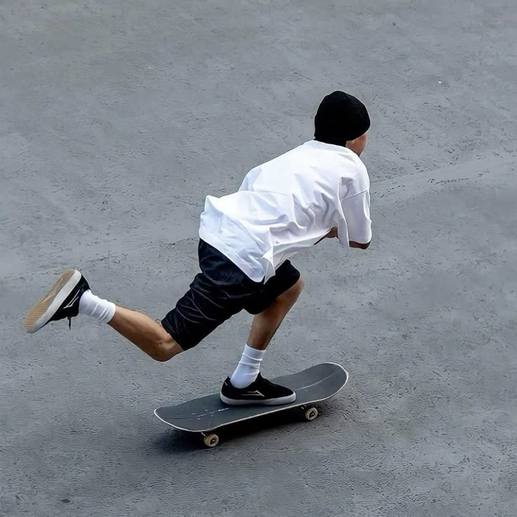 Ein cooler Skater von der Seite mit Mรผtze, Shirt und Shorts auf Asphalt.