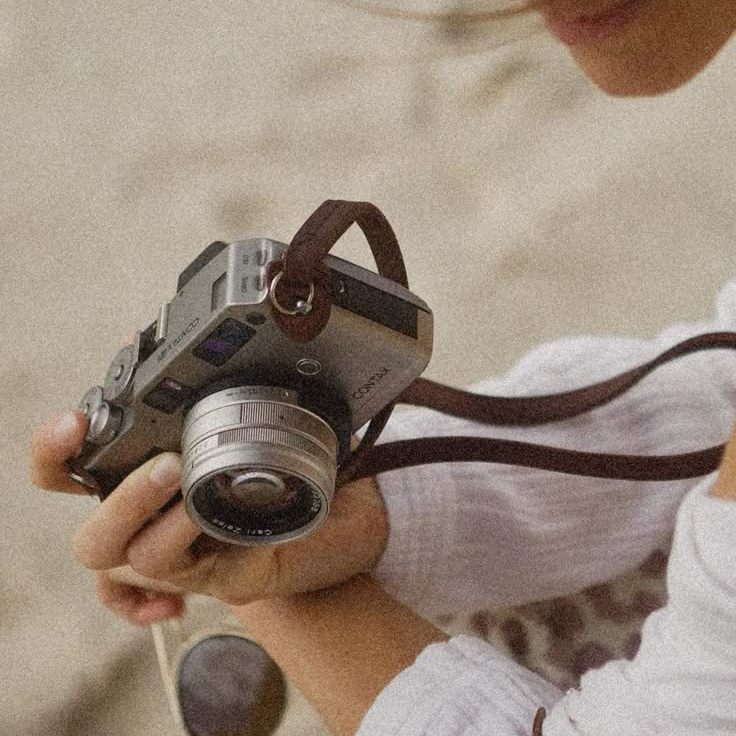 Eine Hand in der eine silberne Kamera gehalten wird.