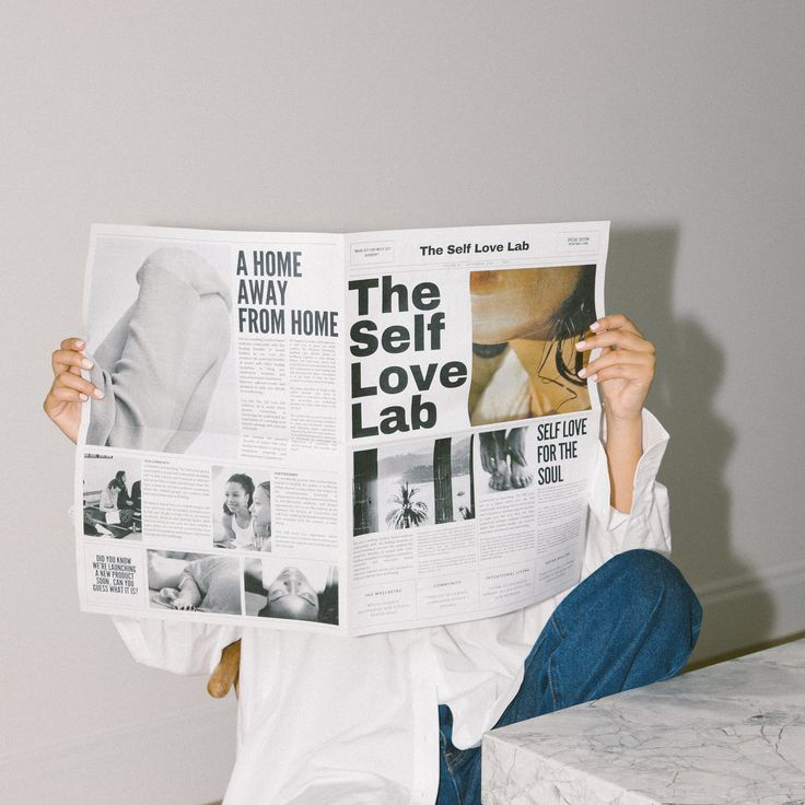 Eine Person deren Gesicht durch ein Design Magazin verdeckt ist.