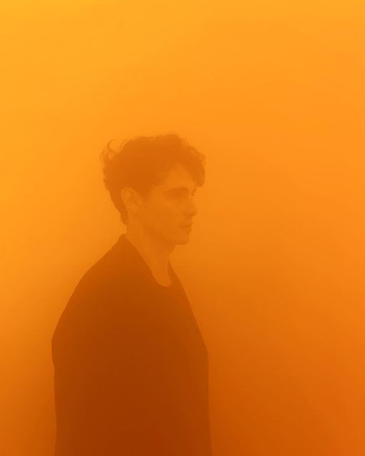 Fotografie von einer mรคnnlichen Person im orangenen Nebel.