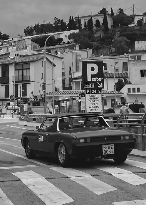 Fotografe in schwarz weiß von einem Oldtimer nach einem Zebrastreifen im Küstenort Cadaques, Spanien.