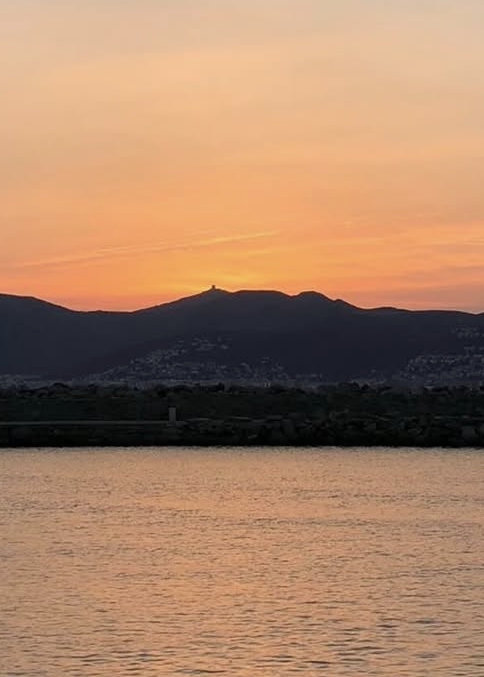 Sonnenaufgang am Meer hinter einem Berg hervor.