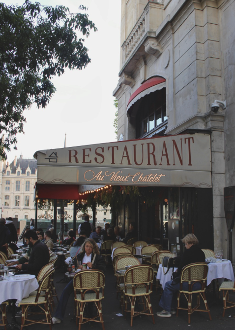 Fotografie aus einem französischen Restaurant in Paris in rot-beige Tönen und vielen Menschen die dort sitzen.